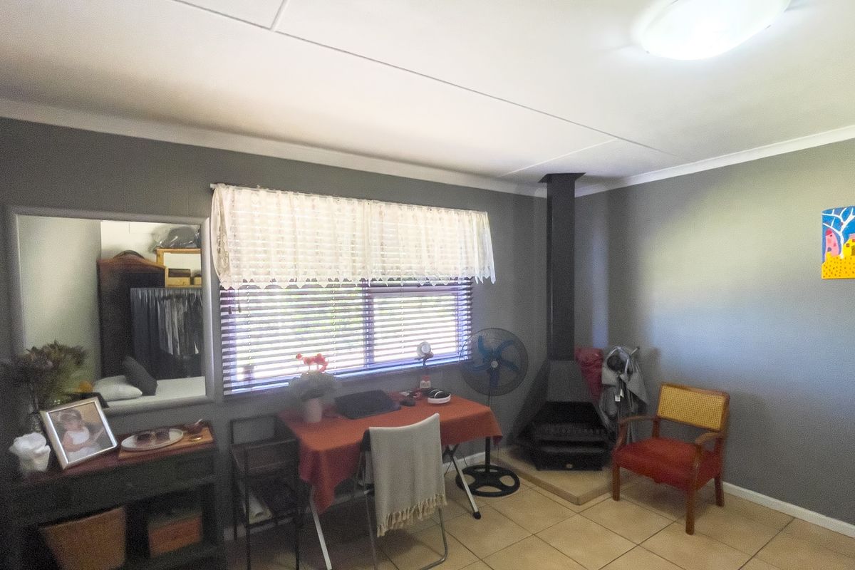 A living room featuring tiled flooring, a freestanding fireplace, and a window with venetian blinds, finished with cove cornicing.