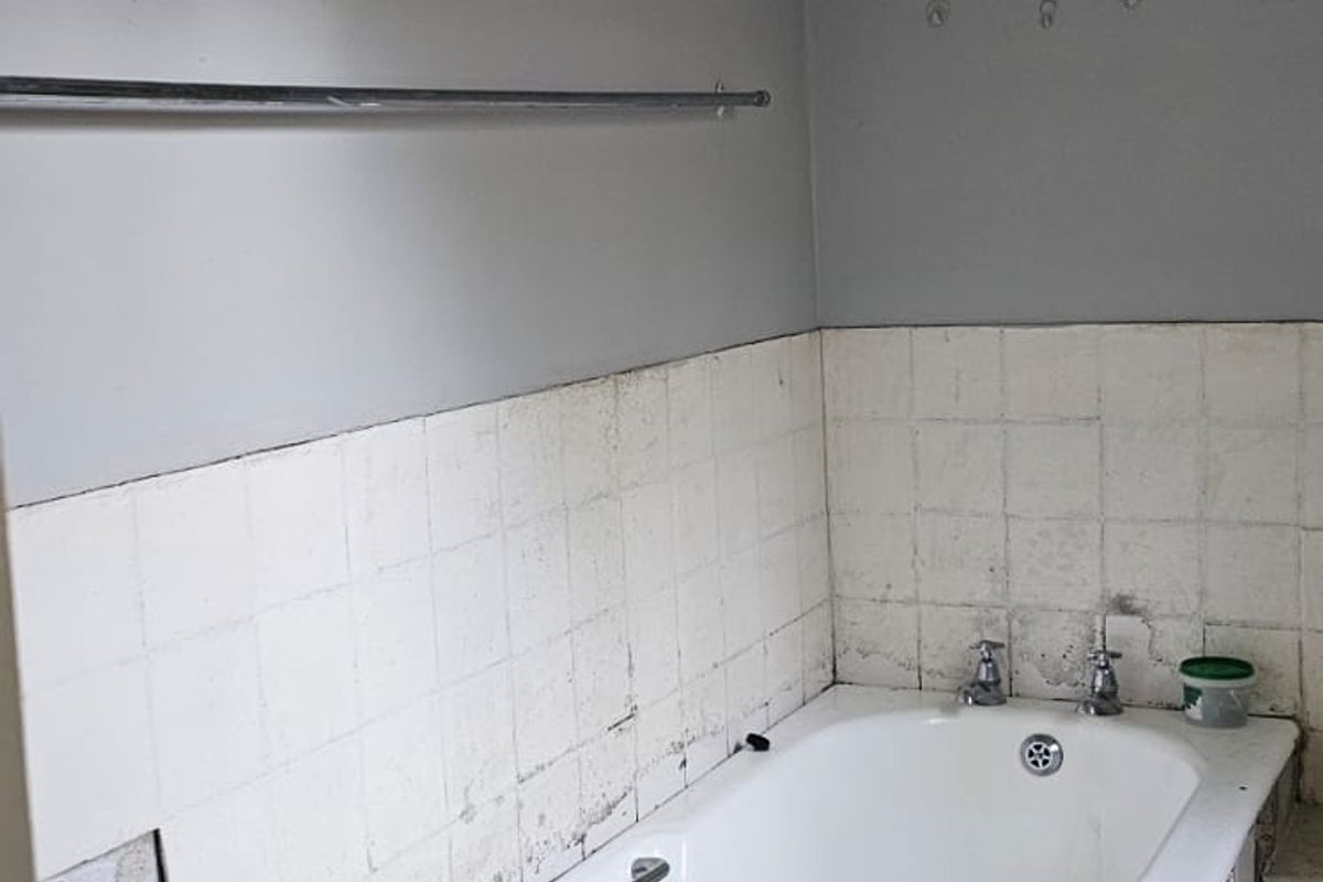 A dated bathroom featuring a built-in bathtub with tiled surround, requiring renovation and updated finishes.