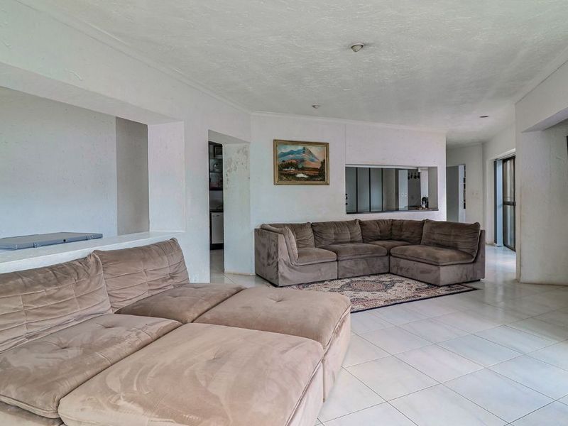 Spacious living area featuring tiled flooring, recessed lighting, and a convenient pass-through window connecting to the kitchen area.