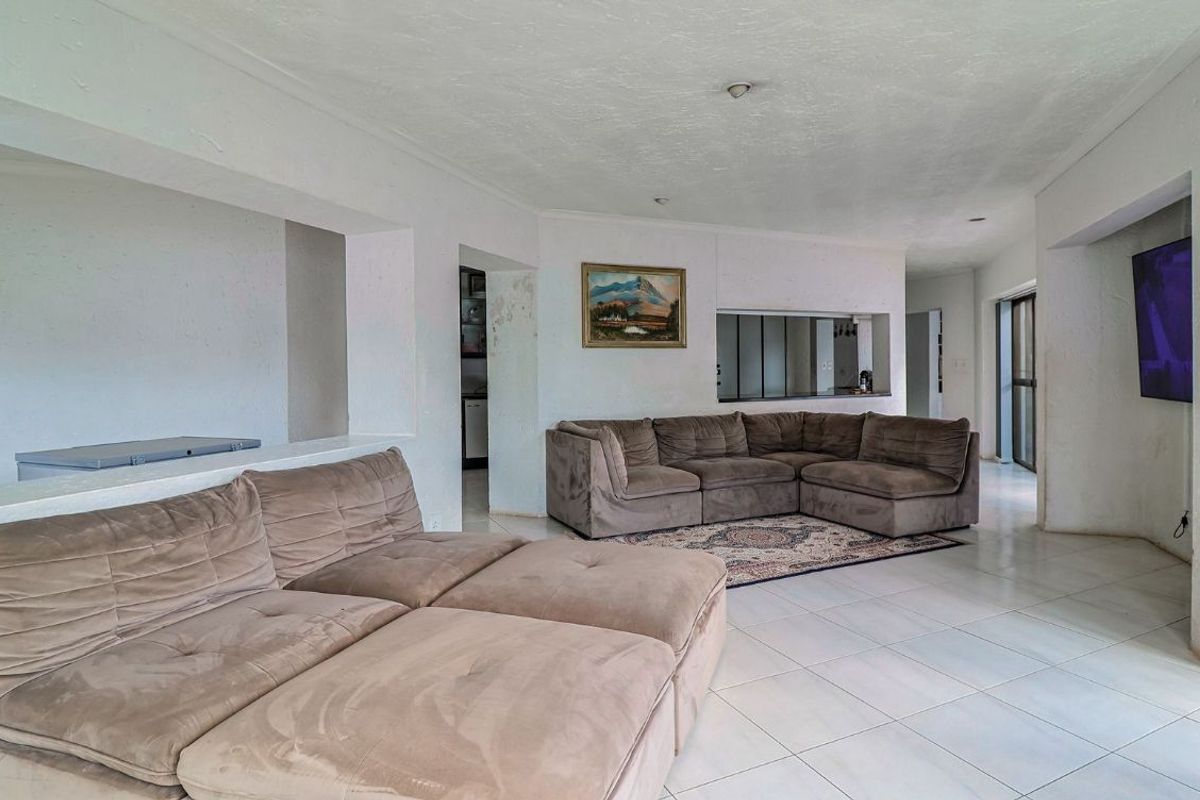 Spacious living area featuring tiled flooring, recessed lighting, and a convenient pass-through window connecting to the kitchen area.