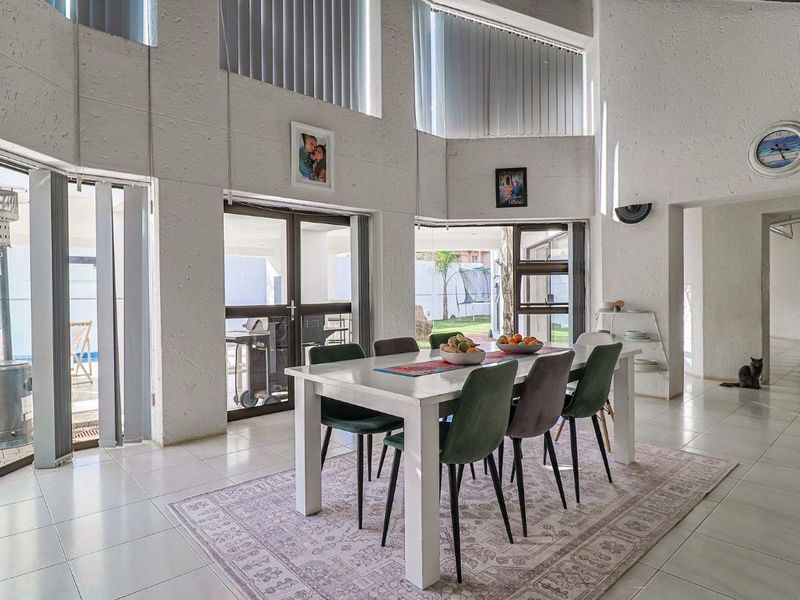 Spacious dining area featuring high ceilings, large sliding glass doors providing natural light, and direct access to the outdoor patio and pool area.