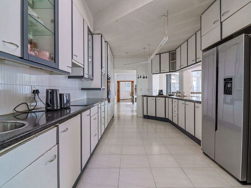 Spacious galley-style kitchen featuring extensive built-in cabinetry, granite countertops, tiled flooring, and a functional layout with integrated appliances.
