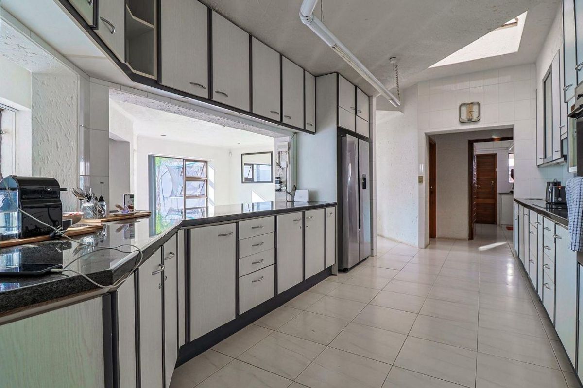 A functional kitchen featuring granite countertops, ample built-in cabinetry, and a skylight, providing a bright and practical workspace.