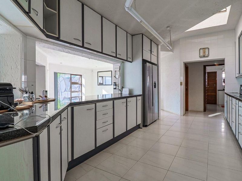 A functional kitchen featuring granite countertops, ample built-in cabinetry, and a skylight, providing a bright and practical workspace.