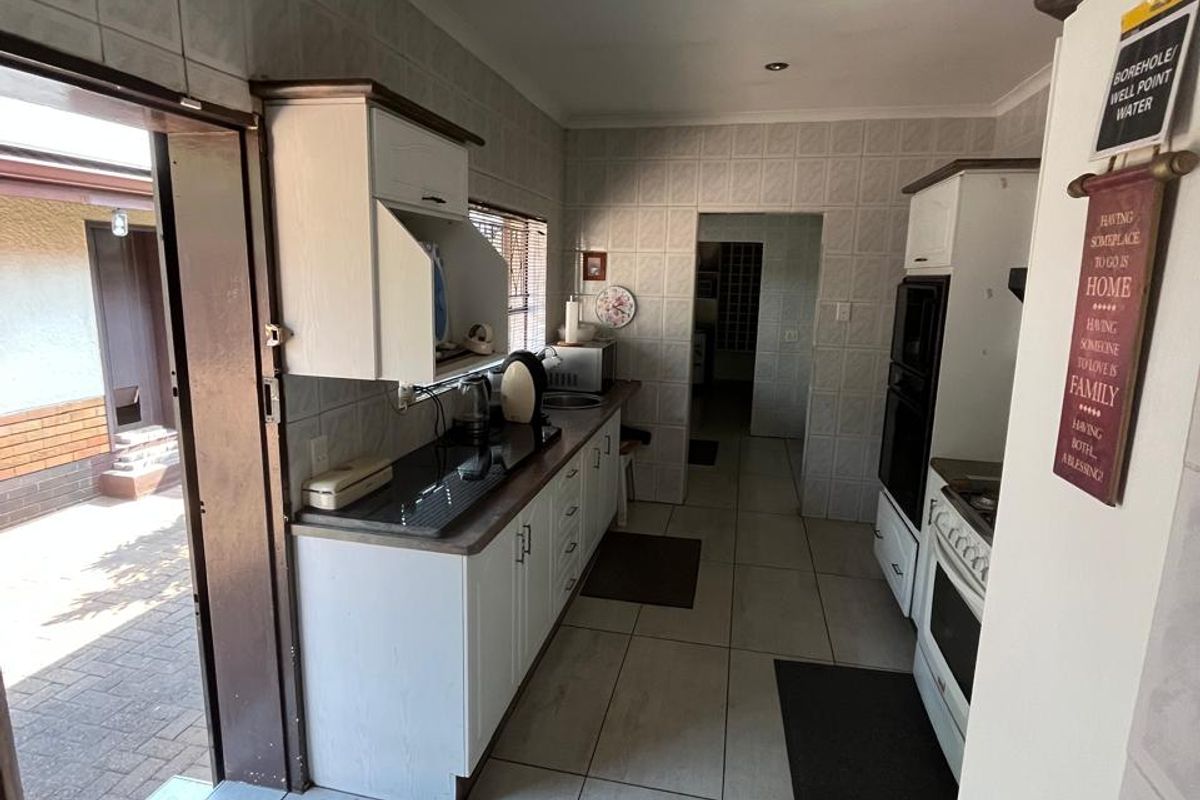 A functional kitchen featuring white cabinetry, built-in oven, and tiled flooring, with direct access to an outdoor patio area.