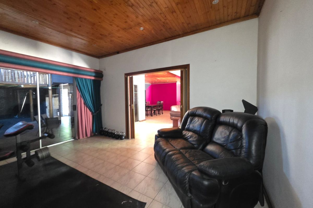 Spacious living area featuring a timber-clad ceiling, tiled flooring, and sliding glass doors leading to an outdoor space.