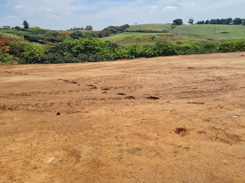 A view of a cleared residential vacant land plot with surrounding natural landscape and rolling hills.