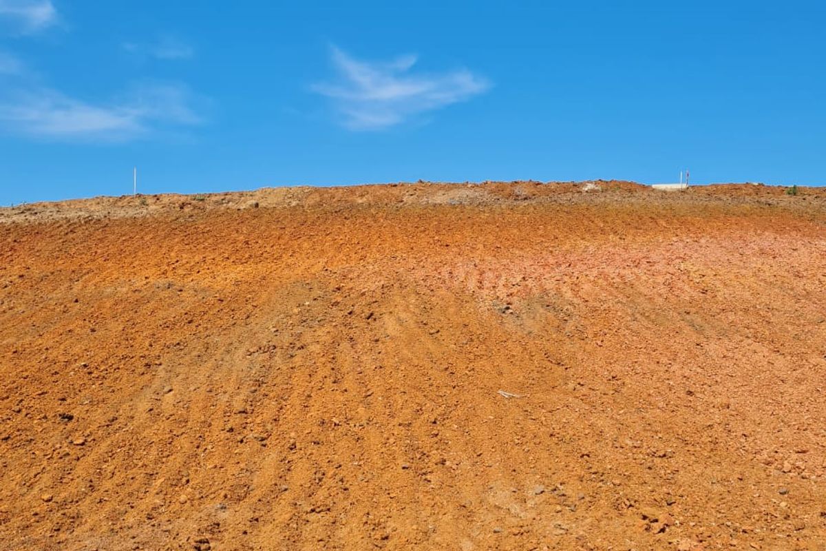 A view of a cleared and graded residential plot of land under a clear blue sky.