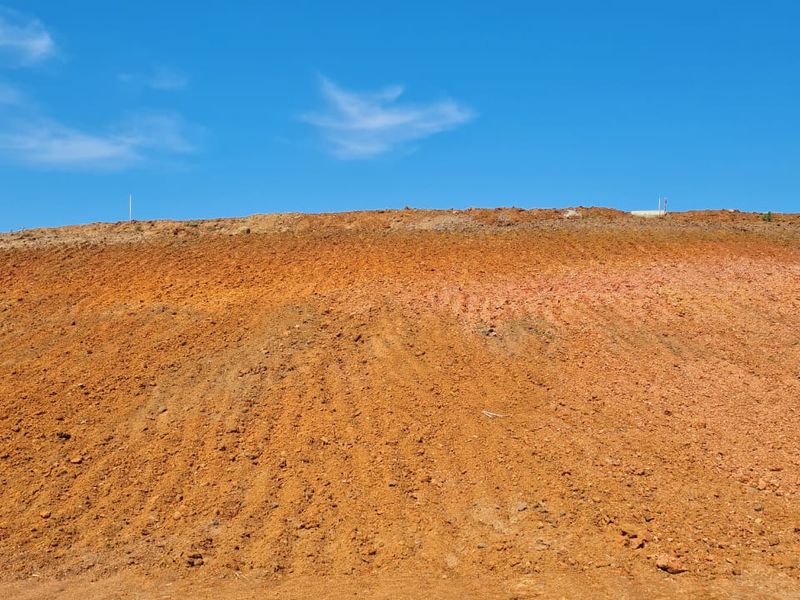 A view of a cleared and graded residential plot of land under a clear blue sky.