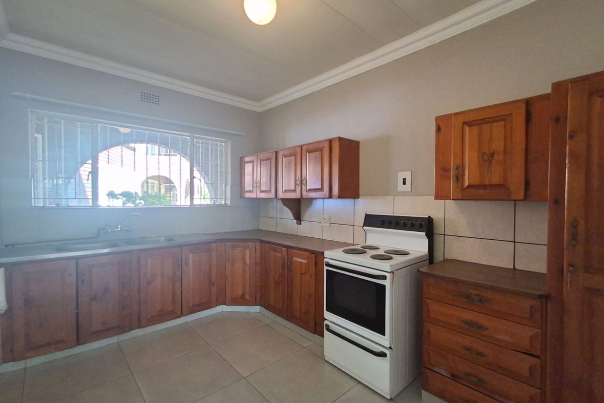 A functional kitchen featuring wooden cabinetry, tiled flooring, a built-in sink, and a freestanding stove.
