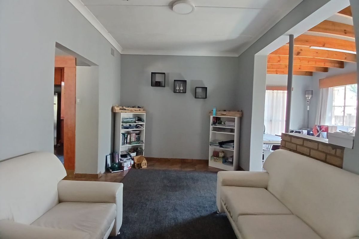 A living room featuring neutral walls, tiled flooring, and an open-plan layout connecting to adjacent living spaces.