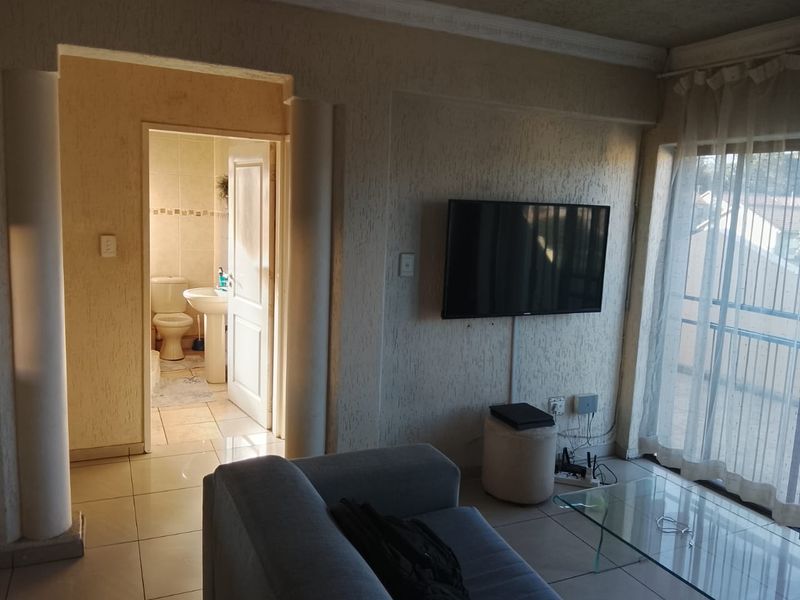 Living room featuring tiled flooring, textured walls, and direct access to a balcony, with an adjacent bathroom visible through the doorway.