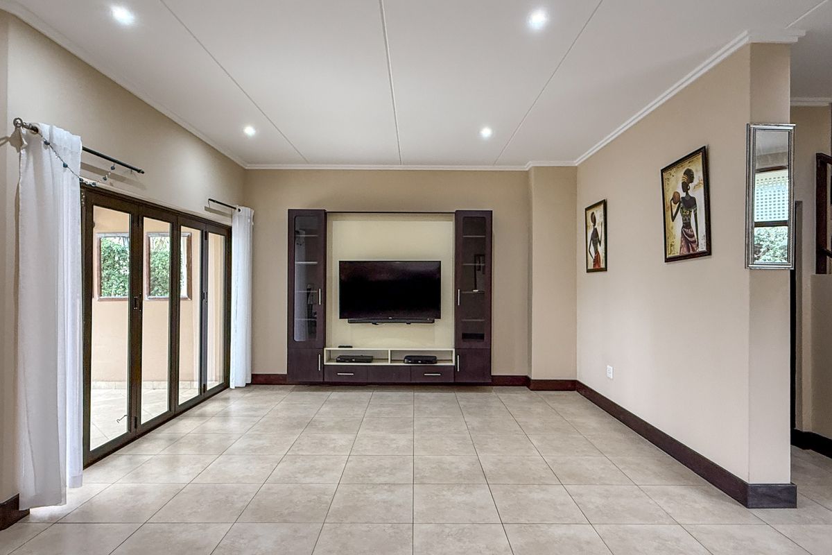 Spacious living room featuring tiled flooring, recessed ceiling lighting, and large glass sliding doors providing access to the outdoor area.