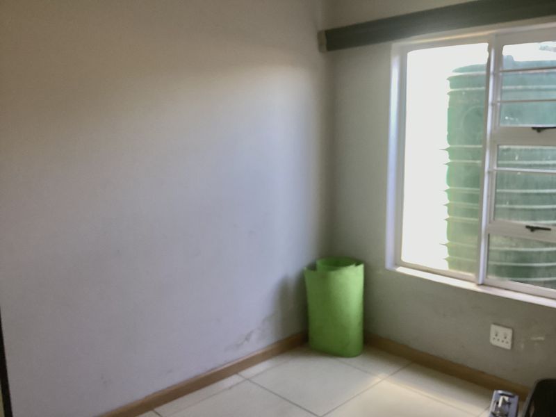 An empty bedroom featuring tiled flooring and a window with an aluminium frame, requiring minor cosmetic updates to the walls.