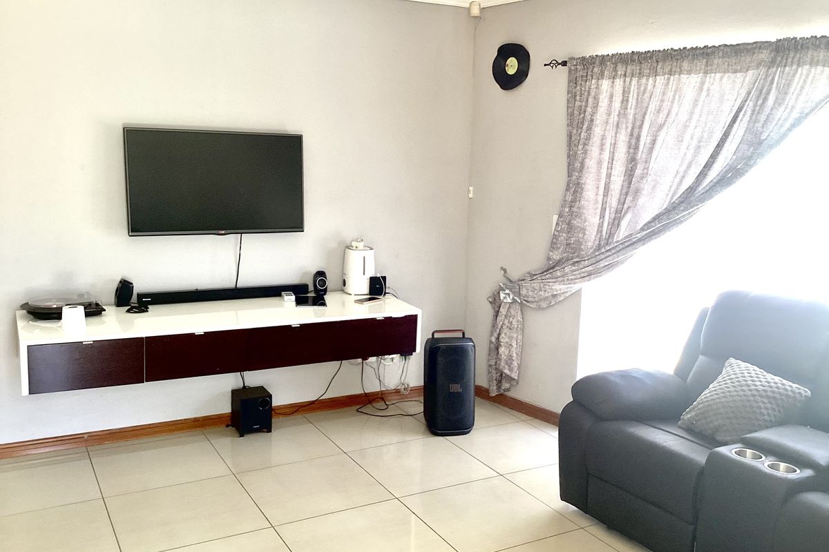 A living room featuring tiled flooring and a wall-mounted media console, providing a functional space for entertainment.