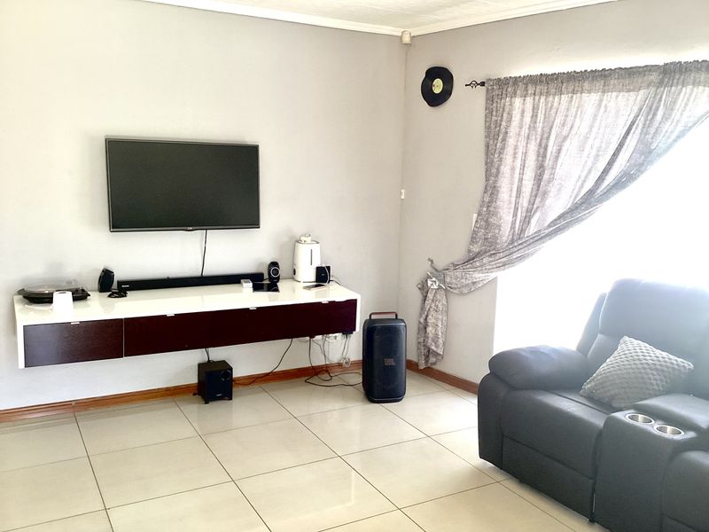 A living room featuring tiled flooring and a wall-mounted media console, providing a functional space for entertainment.