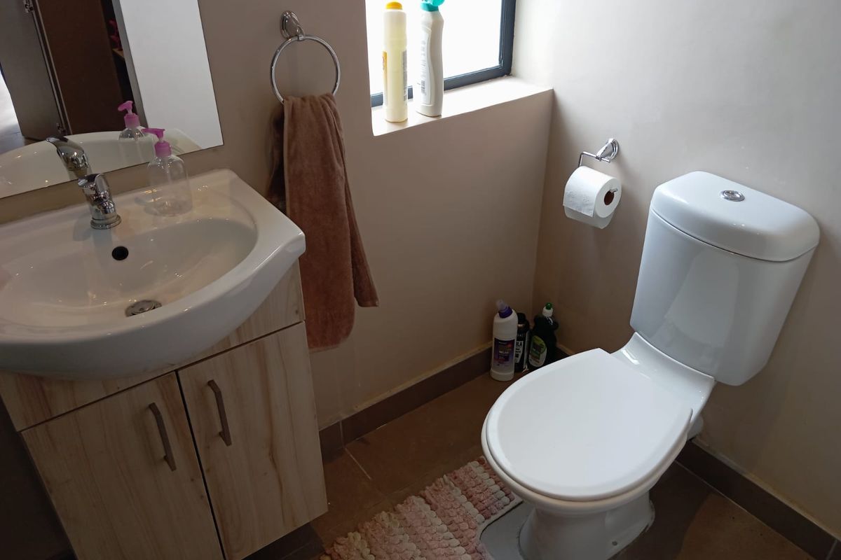 A compact bathroom featuring a modern vanity with a basin, a wall-mounted mirror, and a standard white toilet.