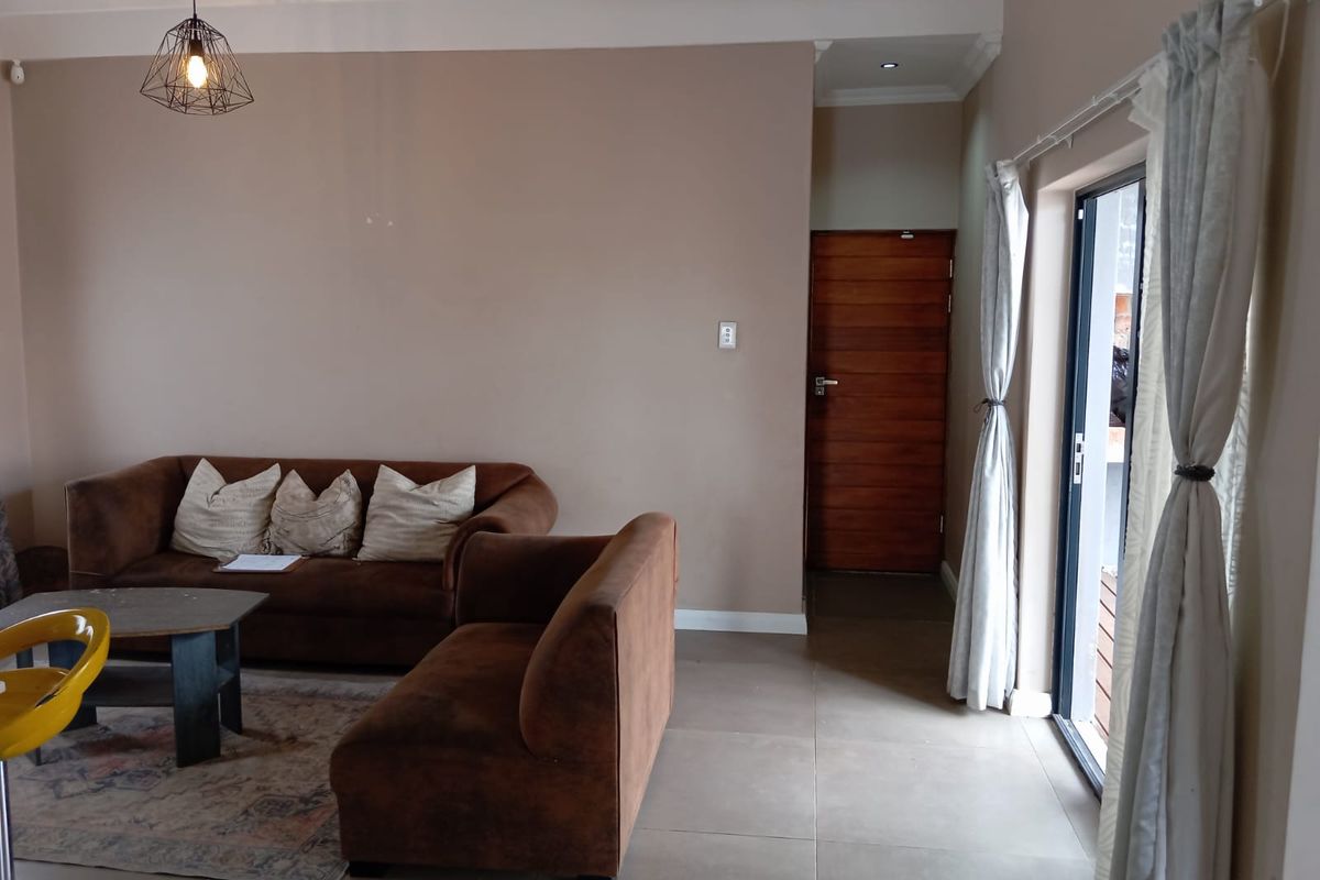 A living room featuring tiled flooring, a wooden door, and a sliding glass door providing access to the exterior.