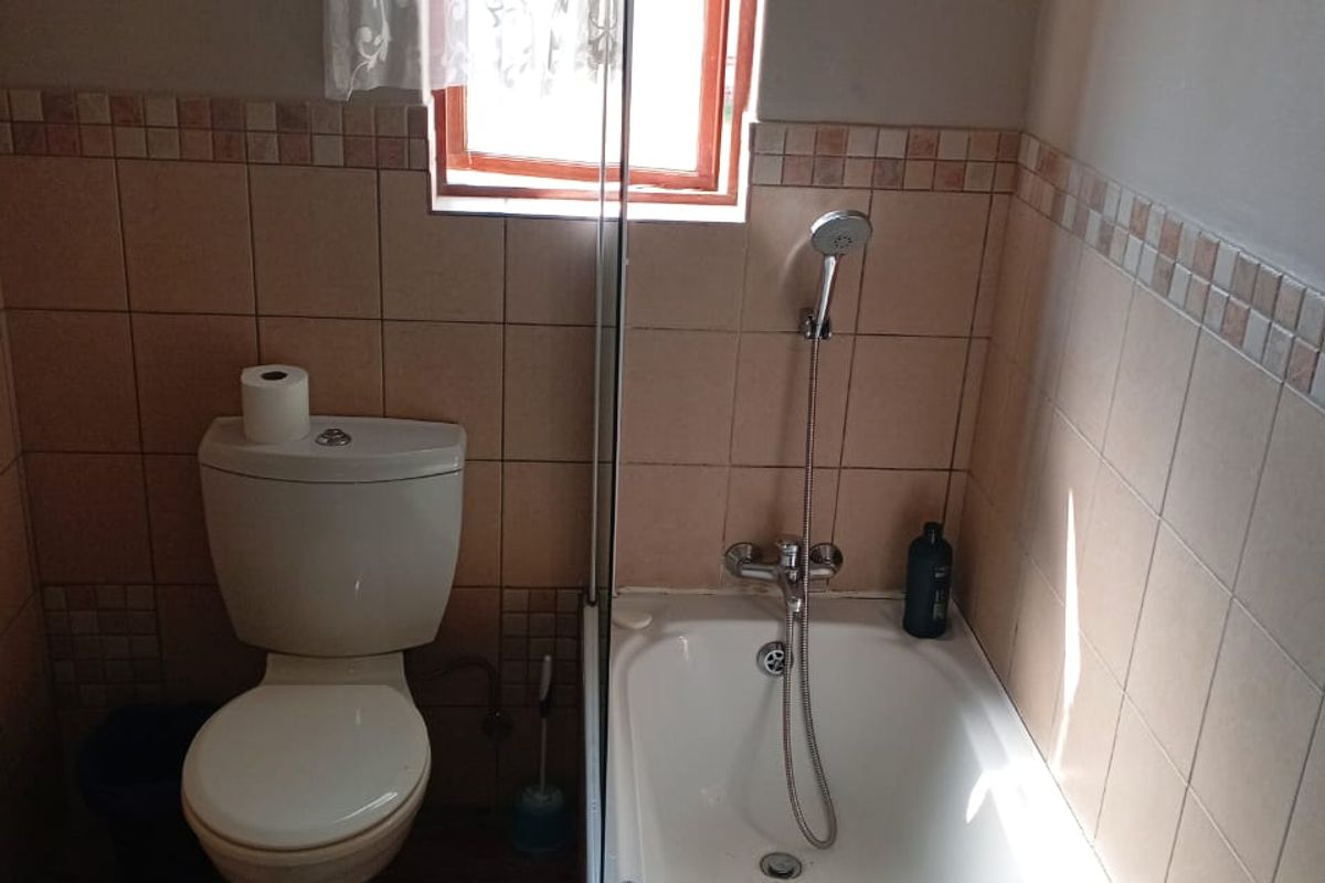 A functional bathroom featuring a standard bathtub with a handheld shower attachment, a toilet, and tiled wall finishes.