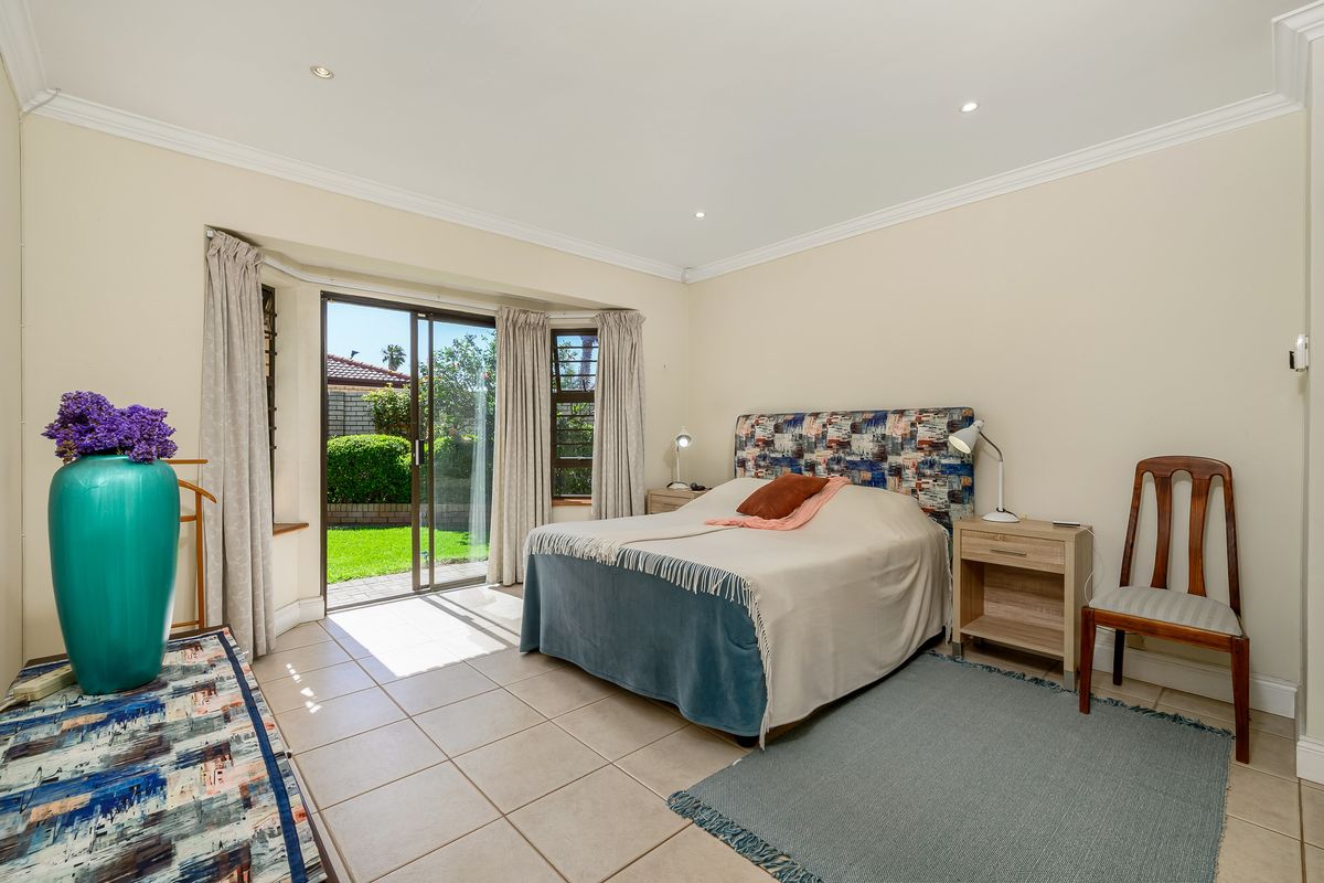 Spacious bedroom featuring tiled flooring, recessed lighting, and large sliding glass doors providing direct access to the rear garden.