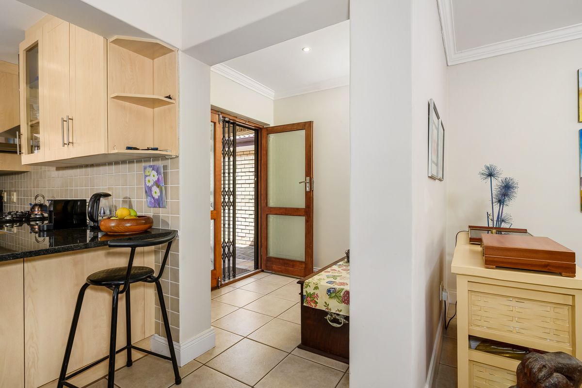 A view from the kitchen looking towards the exterior entrance, featuring light wood cabinetry, granite countertops, and tiled flooring throughout.