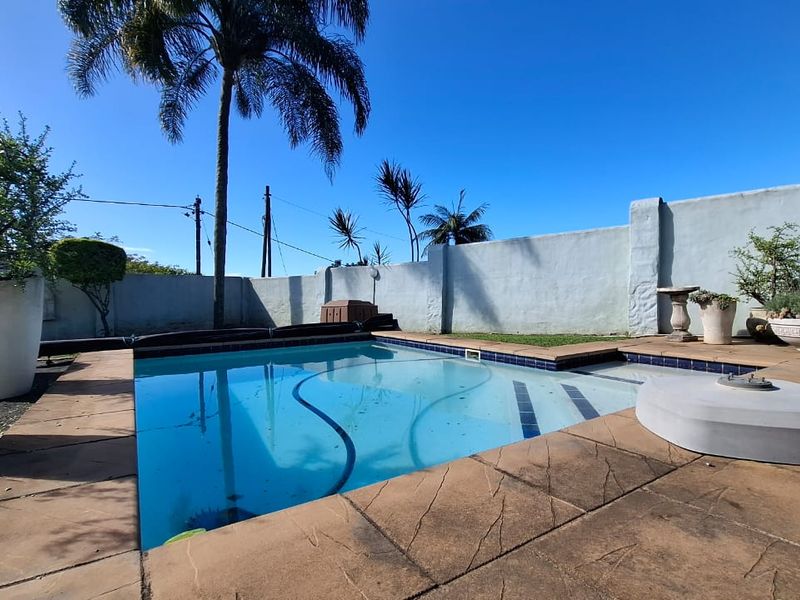 Outdoor pool area featuring a swimming pool with a paved deck and a surrounding perimeter wall.