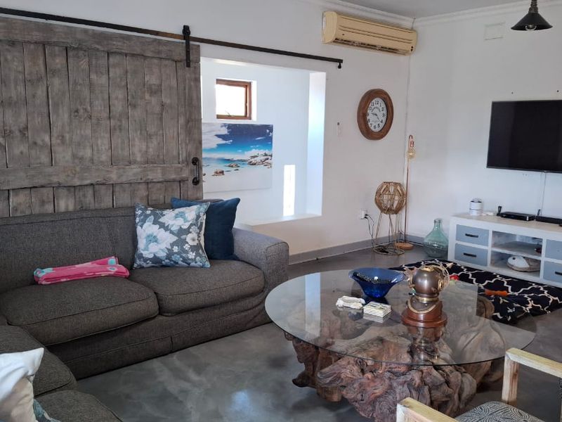 A living room featuring polished concrete floors, a rustic sliding barn door, and a wall-mounted split-system air conditioner.