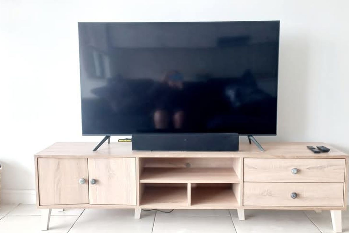 A living room area featuring light-toned tiled flooring and a neutral wall backdrop, suitable for a media setup.