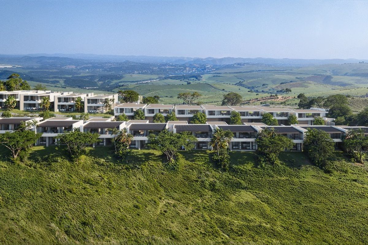 An elevated aerial view of a modern townhouse complex nestled in a scenic, green hillside landscape with expansive valley views.