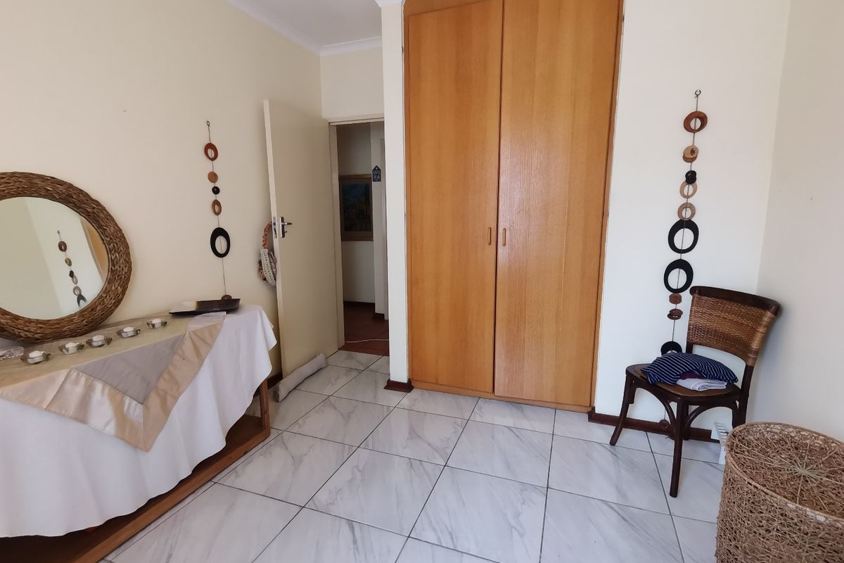 A bedroom featuring light-colored tiled flooring and a built-in wooden wardrobe, providing functional storage space within the room.