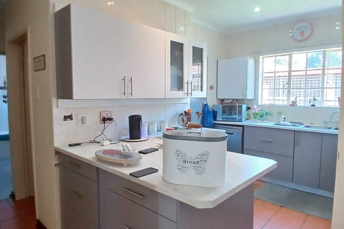 A functional kitchen featuring grey cabinetry, laminate countertops, tiled flooring, and a double sink with a window view.