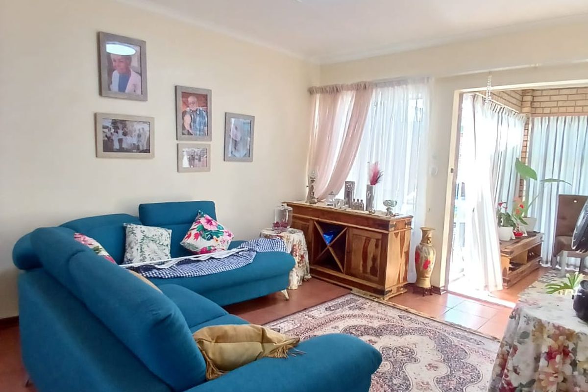 A comfortable living room featuring tiled flooring and a sliding glass door that provides access to an adjoining patio area.
