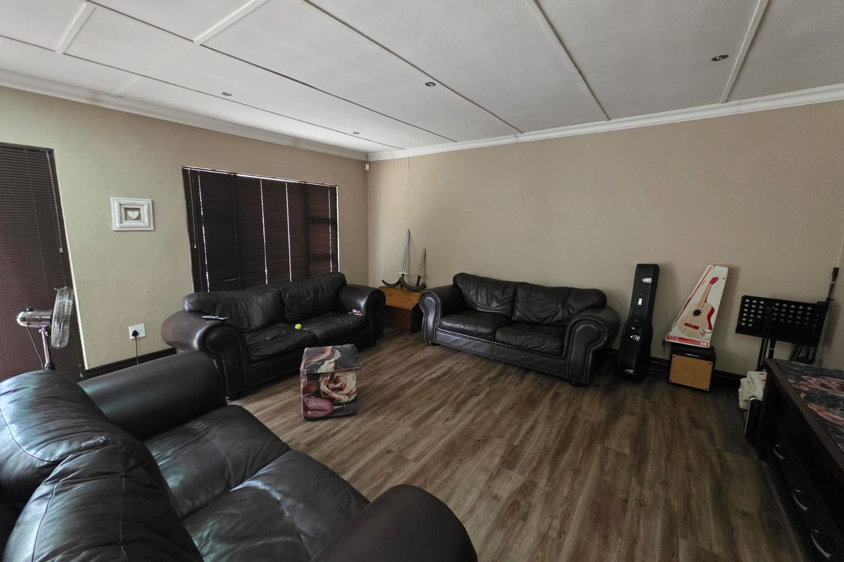 Spacious living room featuring wood-look laminate flooring, recessed ceiling lighting, and dark window blinds.