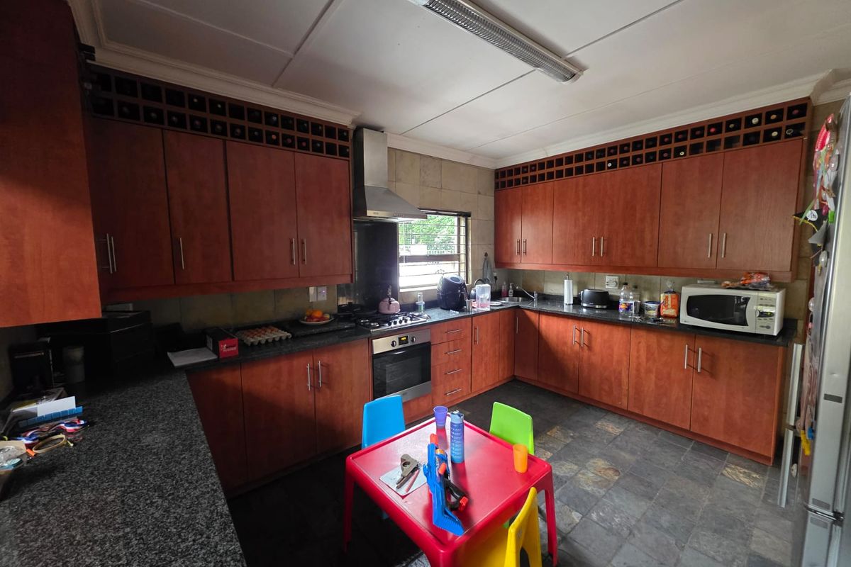 Spacious kitchen featuring dark wood cabinetry, granite countertops, built-in oven, extractor fan, and tiled flooring with ample storage space.