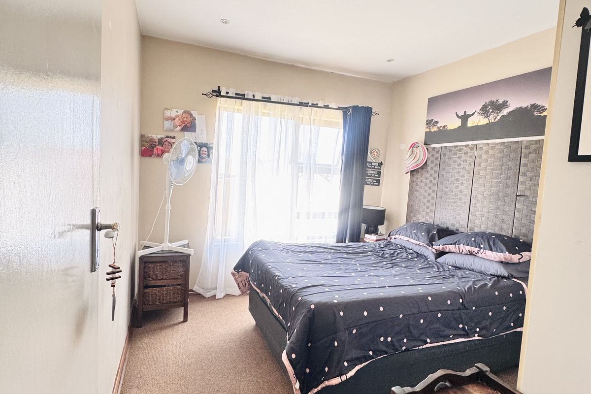 A bedroom featuring carpeted flooring, a built-in headboard, and a window with curtain tracks.