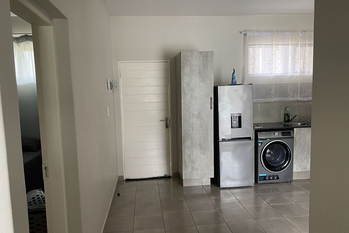 A functional kitchen area featuring tiled flooring, built-in cabinetry, and a dedicated space for laundry appliances.