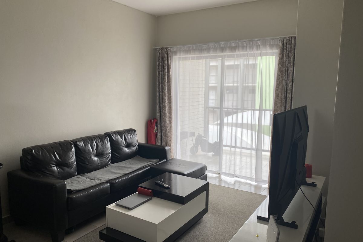 A living room featuring tiled flooring and large sliding glass doors that provide access to an outdoor balcony area.