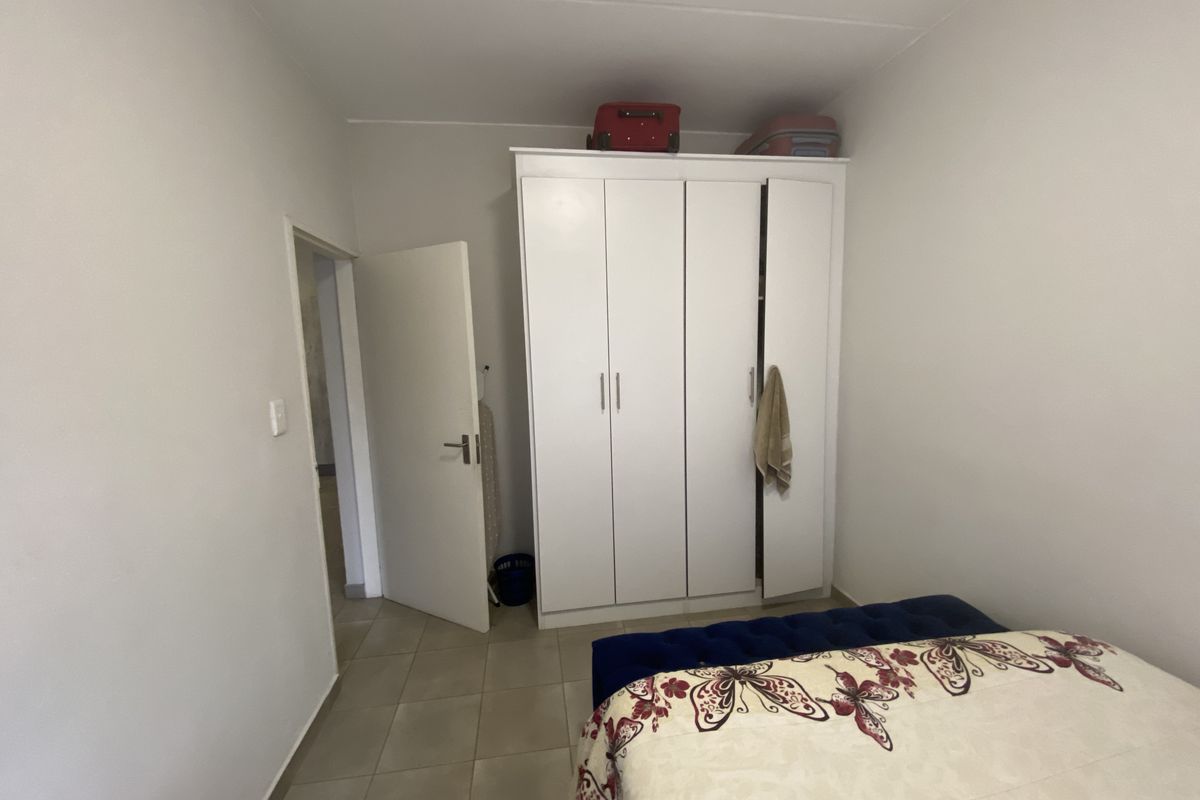 A bedroom featuring built-in white cabinetry and tiled flooring, providing functional storage space within the townhouse.