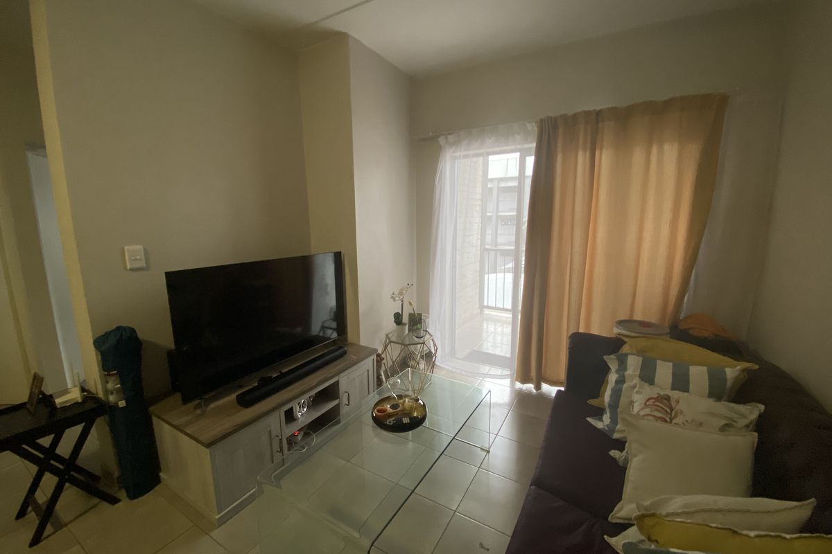 A living room featuring tiled flooring and a sliding glass door providing access to an outdoor balcony area.