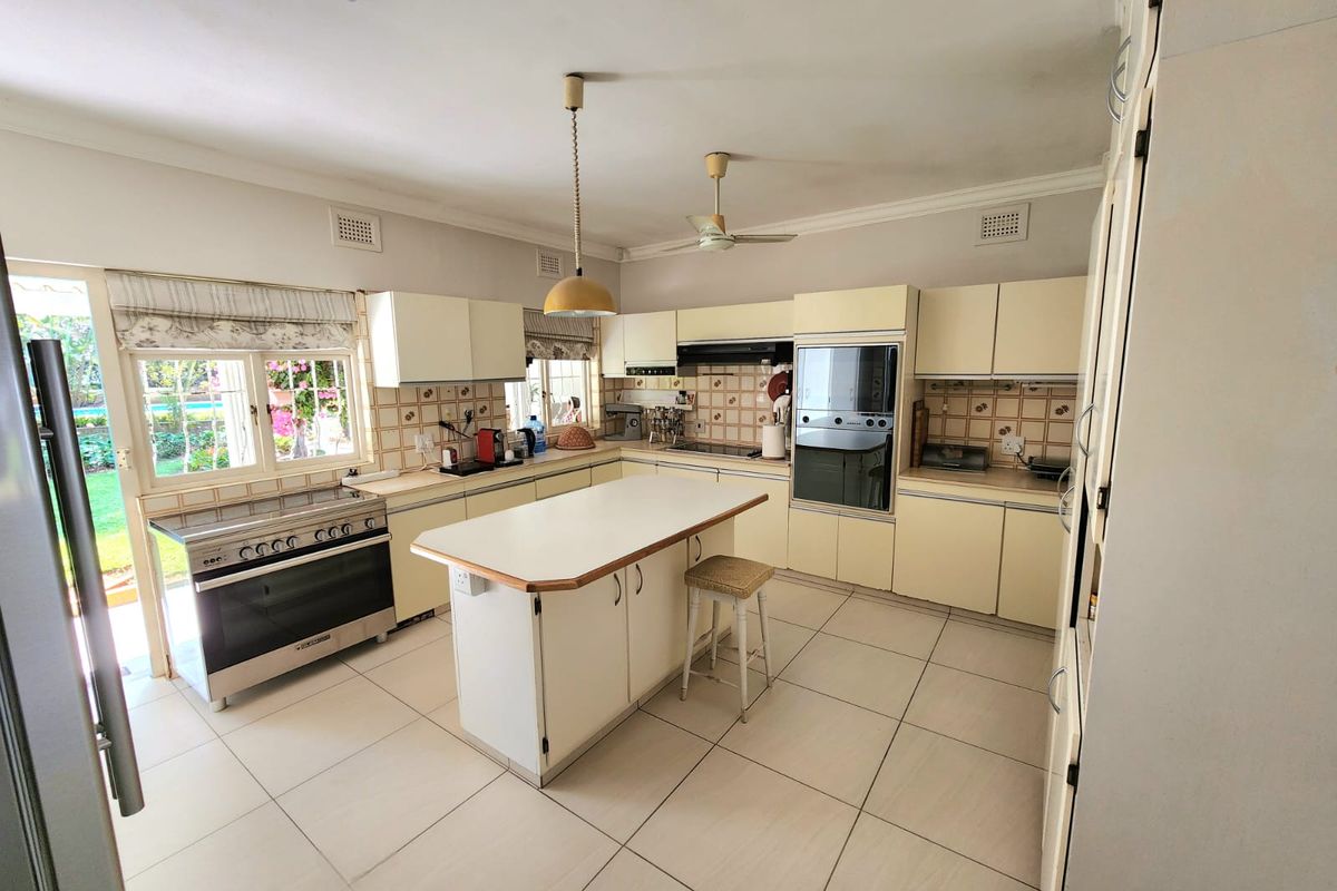 Spacious kitchen featuring a central island, built-in oven, extractor fan, and ample cabinetry, with direct access to the garden area.