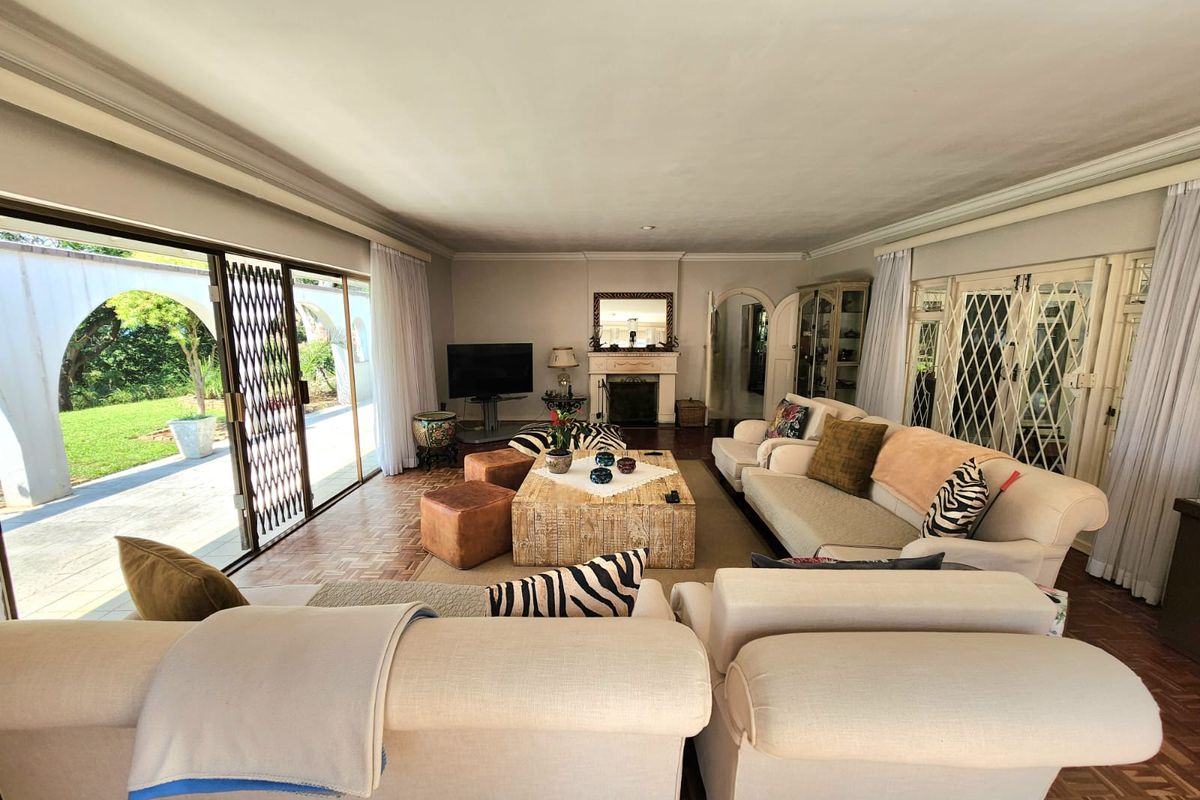 Spacious living room featuring a classic fireplace, parquet flooring, and large sliding glass doors providing seamless access to the outdoor patio and garden area.