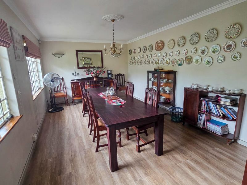 A spacious dining room featuring laminate flooring, decorative coving, and a classic chandelier, providing a functional space for family meals and entertaining.