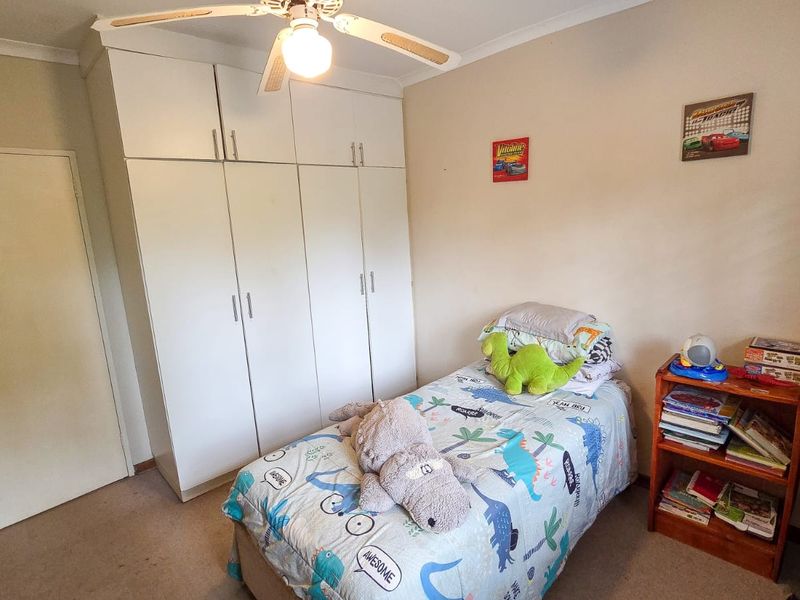 A functional bedroom featuring built-in cupboards and a ceiling fan, providing practical storage and climate control.