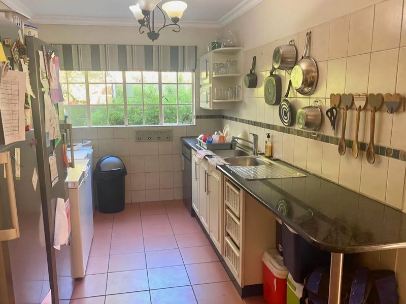 A functional kitchen featuring granite countertops, tiled backsplash, and ample cabinetry, offering a practical layout with a window overlooking the garden.