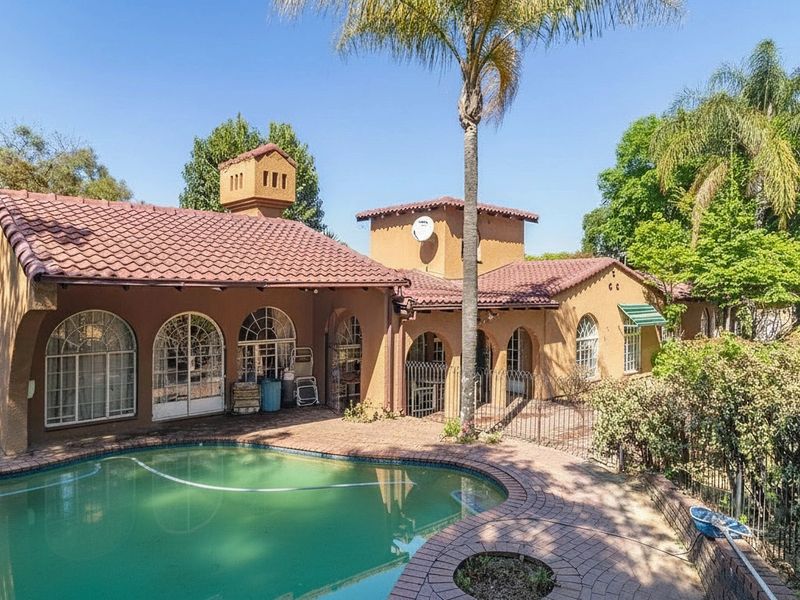 Rear exterior view of the house featuring a swimming pool, brick paved patio area, and traditional arched windows under a tiled roof.