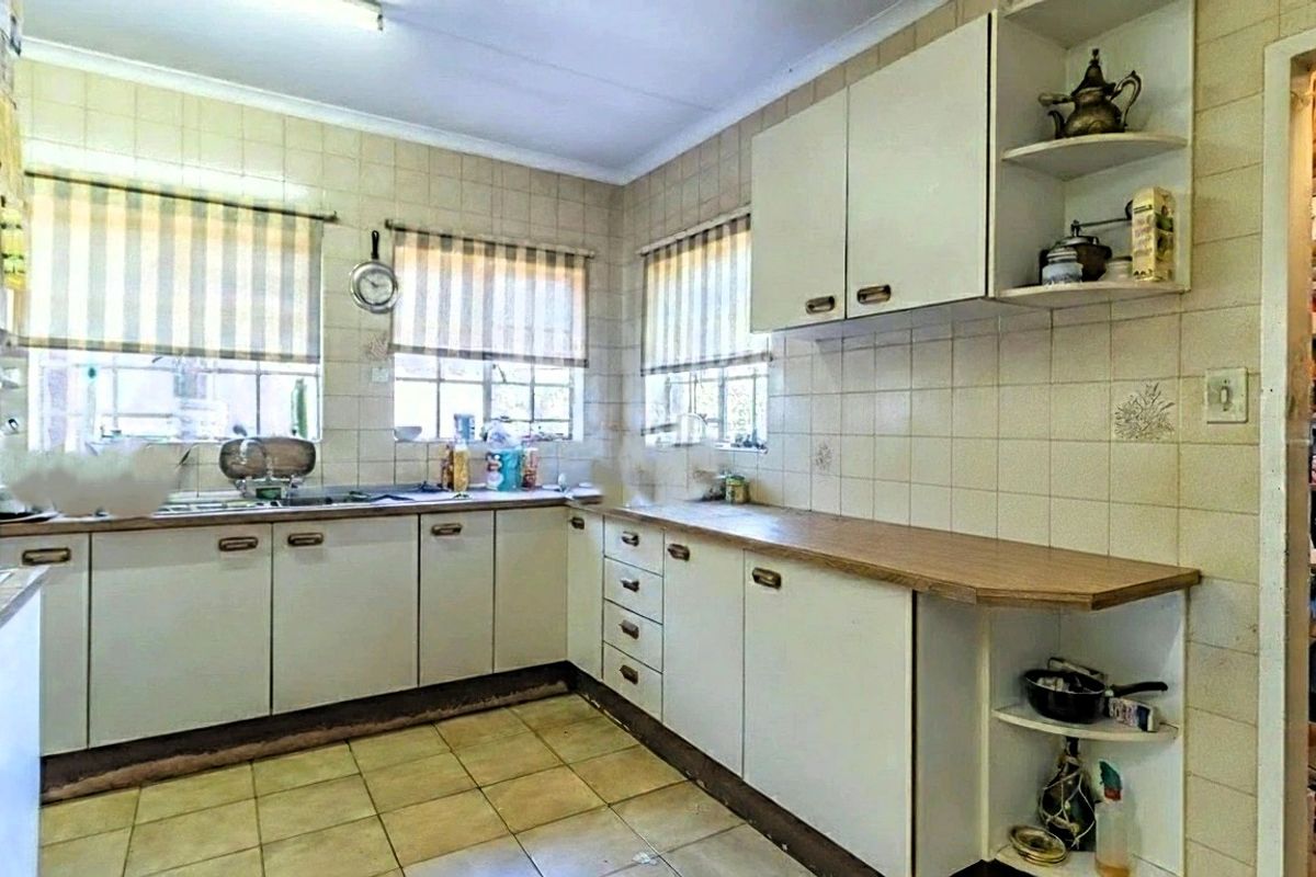 A functional kitchen featuring laminate countertops, tiled splashbacks, and ample built-in cabinetry, offering a dated aesthetic ready for modernization.