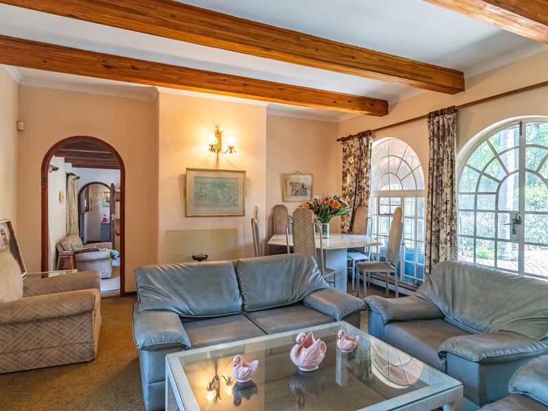 Open plan living and dining area featuring exposed timber ceiling beams, arched windows, and an arched doorway leading to an adjacent room.