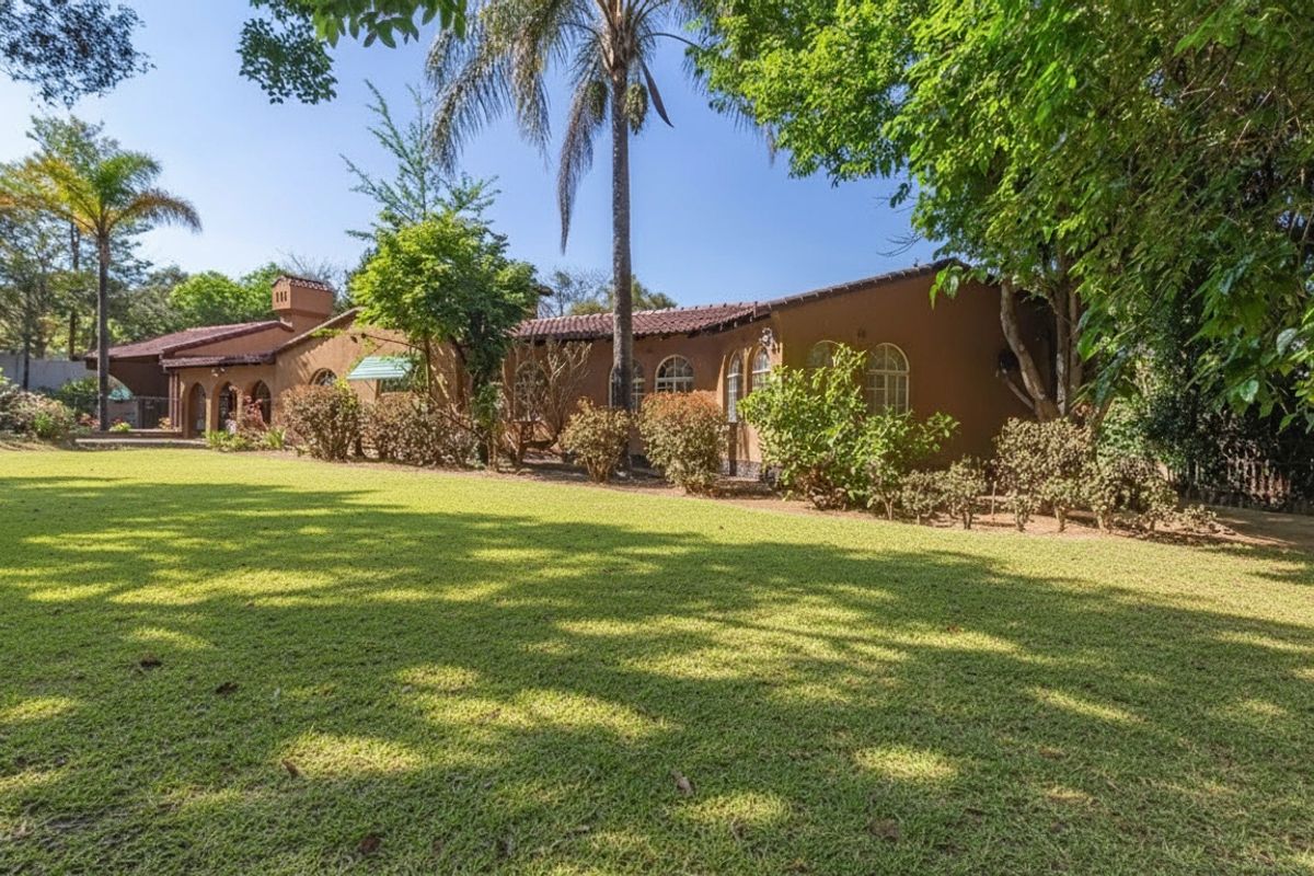 A view of the rear elevation of the house featuring a large, well-maintained lawn and mature garden landscaping.