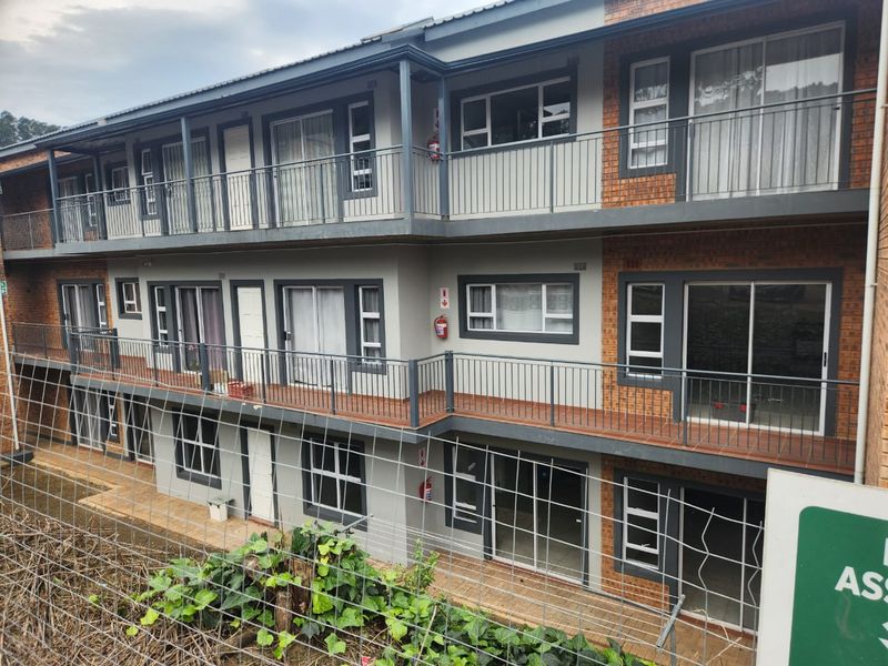 A multi-story apartment building exterior featuring brick and plaster finishes, private balconies with metal railings, and sliding glass door access to units.