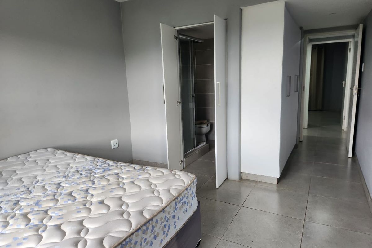 A bedroom featuring tiled flooring, built-in cupboards, and direct access to an en-suite bathroom.